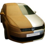 Fotografiert ist ein 1 zu 1 Plastilin Modell eines VW Polo von 2009, das auf der Fahrerseite fertig foliert ist.