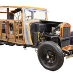 Fotografiert ist ein halb restaurierter Pkw aus der 1930er Jahren, bei dem manche Bleche noch fehlen, so dass die darunter liegende Holzkonstruktion gut zu erkennen ist.