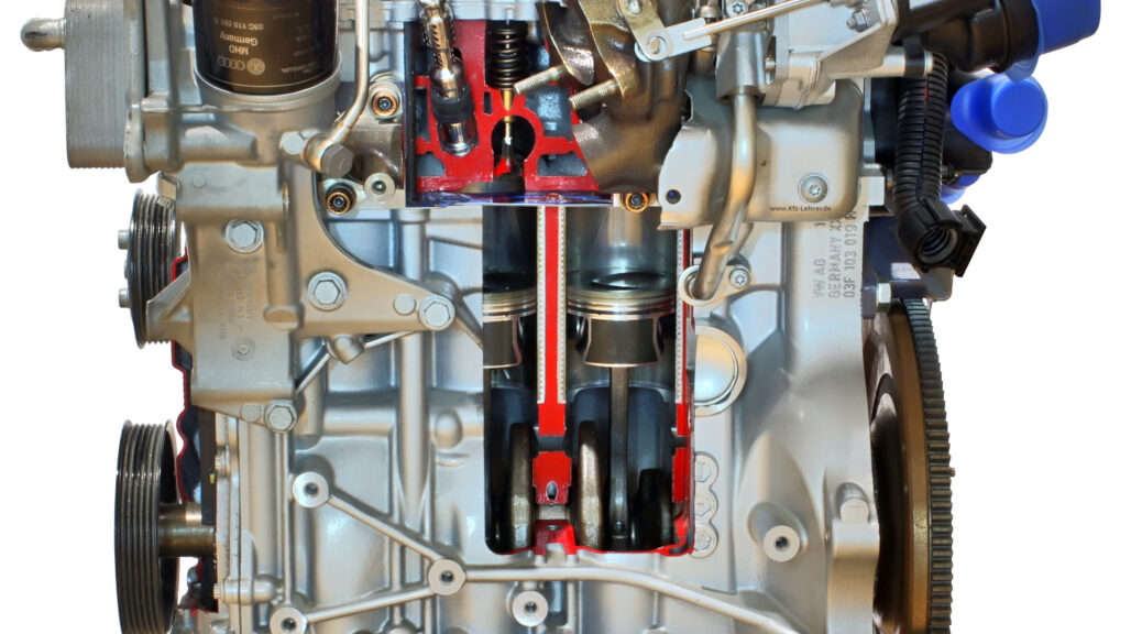 Fotografiert ist der Reihenmotor EA111 von der Seite. Der Motor ist ein Schnittmodell, so dass die Kolben und die Pleuel im Motorblock sichtbar sind.