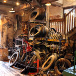 Blick auf ein Reifenlager in einer historischen Werkstatt, hier der Bereich des Vulkaniseurs. Es stapeln sich Reifen, Felgen und Schläuche